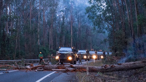 Australian Defence Force troops and members of Forest Fire Management Victoria clear felled trees on the Princes Highway just outside Genoa. 