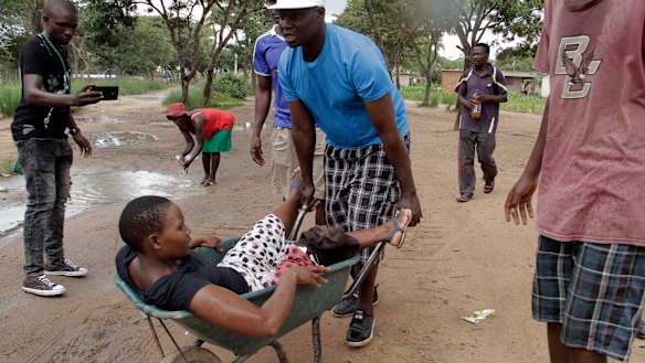 A woman with a wounded leg during clashes between protesters and police is transported in a wheelbarrow, during the protests in Harare.