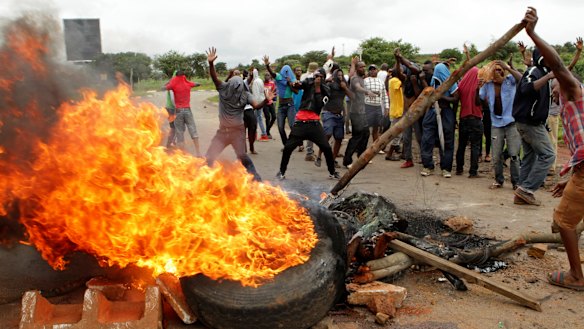 Protesters gather near a burning tyre during a demonstration over the rise in fuel prices in Harare, Zimbabwe, on Tuesday.