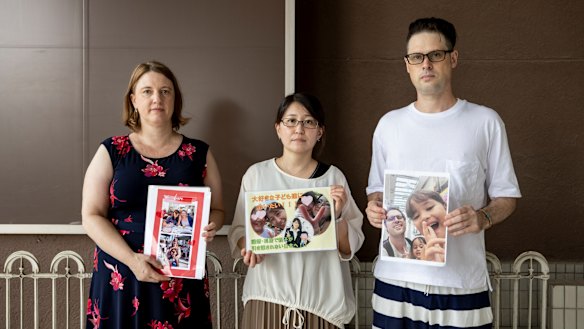 Catherine Henderson, Izumi Dobashi and Scott McIntyre hold photos up of their children. 