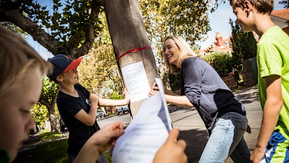 Kate Adamson and her sons; Banjo 11, Rupert 9 and Alastair 6, pin posters up around Elwood's streets offering help to the elderly during the coronavirus pandemic. 