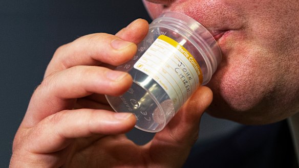 A person demonstrates a COVID-19 saliva test.