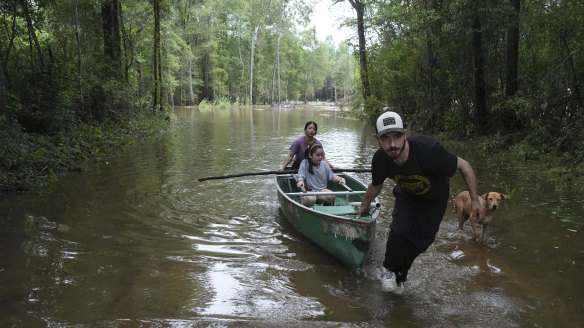Alvaro Trevino pulls a canoe with Jennifer Tellez and Ailyn, 8, after they checked on their home after flooding in Spendora, Texas.