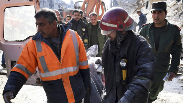 In this photo released by the Syrian official news agency SANA, rescue workers carry a victim where, according to SANA, the five-story building collapsed early on Saturday, killing 11.