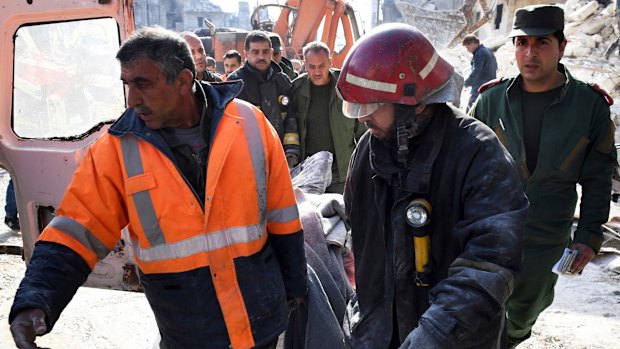 In this photo released by the Syrian official news agency SANA, rescue workers carry a victim where, according to SANA, the five-story building collapsed early on Saturday, killing 11.