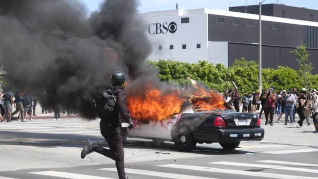A police car burns during protests in Los Angeles.