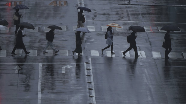 People walk on a pedestrian crossing in the rain in Tokyo. Japan is expecting its 10th typhoon this year.