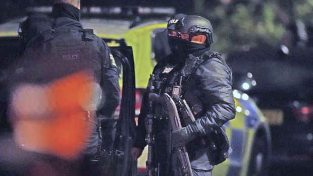 An armed police officer holds a breaching shotgun, used to blast the hinges off a door, at an address police believe connected to the Remembrance Day bombing in Liverpool, England.