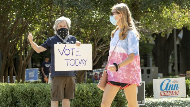 Kim Ludeke, left, encourages UT students to vote at an early voting location at the Gregory Gymnasium on the University of Texas campus in Austin, Texas.
