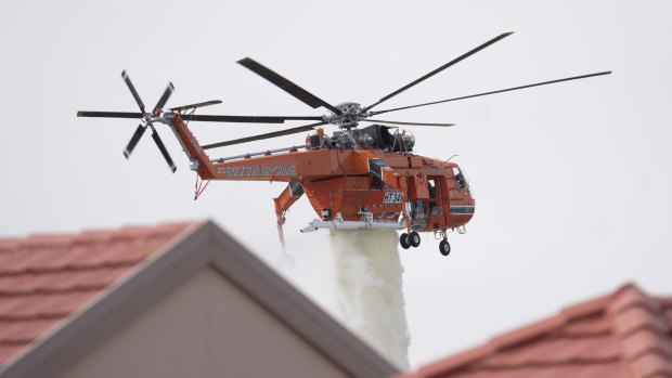 An air-crane drops water to assist firefighters as they battle a grass fire in Taylors Lakes on Monday.