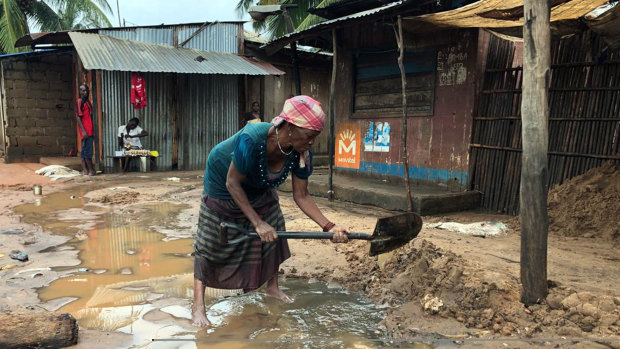 A woman tries to create a drainage system outside her shop in Pemba, Mozambique on Sunday.