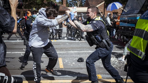 A police officer uses capsicum spray on a protester during Melbourne’s anti-lockdown rally. 