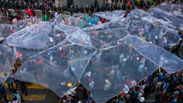 Protesters cover themselves prepare to be sprayed by water cannons in Yangon, Myanmar. 