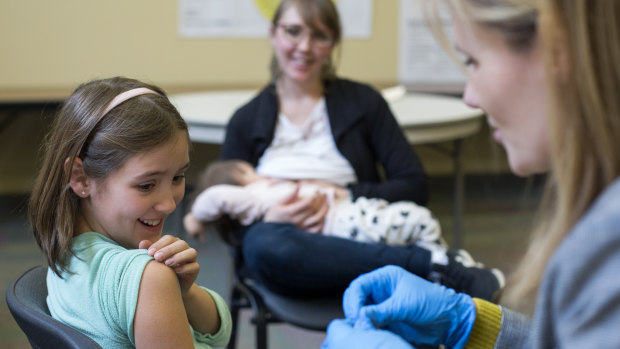 A nine-year-old rolls up her sleeve for a vaccination in Oregon in February of this year.
