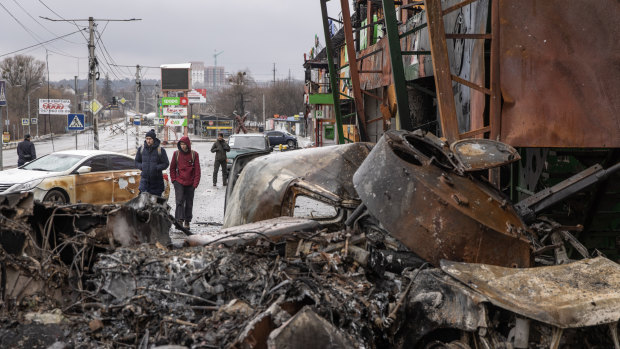 People walk past a destroyed Russian military vehicle at a frontline position  in Irpin, Ukraine.