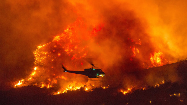A helicopter prepares to drop water at a wildfire in Yucaipa, California, after a couple’s plan to reveal their baby’s gender at a party sparked the blaze at El Rancho Dorado Park.