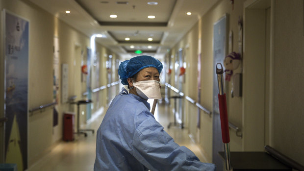 Under control: a cleaner wears a mask as she works at a private maternity hospital in Wuhan, Hubei. 