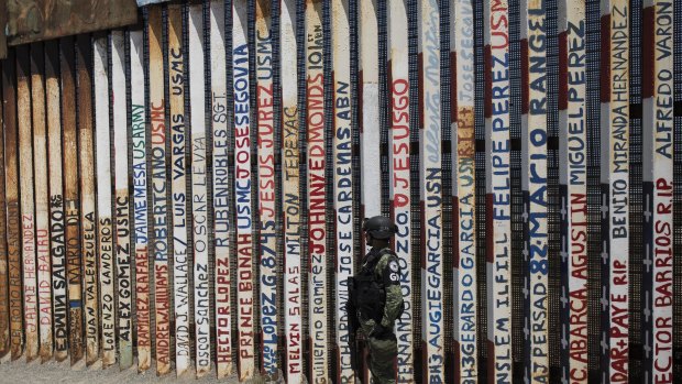 A Mexican National Guard soldier stands guard at a section of the US-Mexico border wall in Tijuana, where the names of deported US military veterans are listed.
