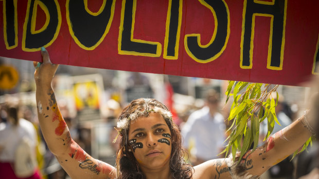 A woman carries a sign calling for the abolition of Australia Day while taking part in the Invasion Day march in Melbourne.