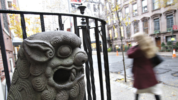 A pedestrian walks past a statue sitting outside the Chinese Institute in New York.