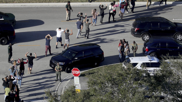 Students hold their hands in the air as they are evacuated by police from Marjory Stoneman Douglas High School in Parkland, Florida.