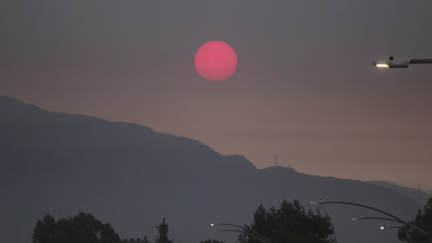 Smoke from wildfires burning east of Los Angeles dims the sunrise on seen from Pasadena, California. 