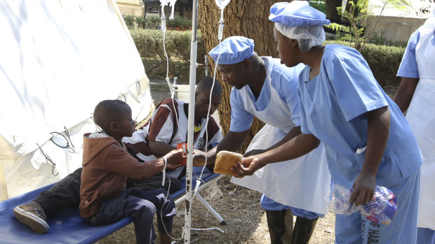 Health workers offer food to a father and son suffering from cholera symptoms at a local hospital in Harare on Tuesday.