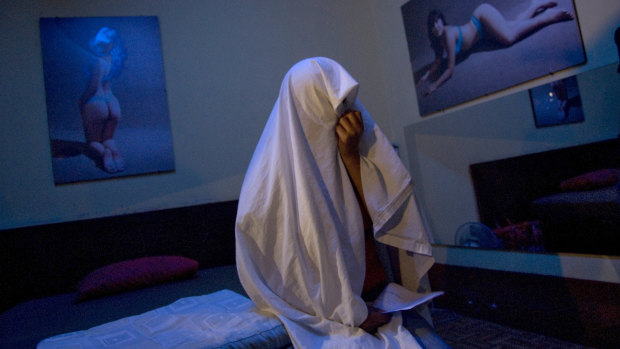 A prostitute covers herself with a sheet as she waits to receive a free HIV/AIDS test at a brothel in Callao, Peru.