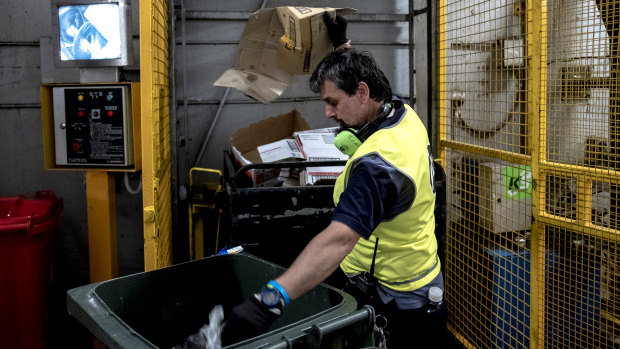 A cleaner sorts recyclable items from general waste.