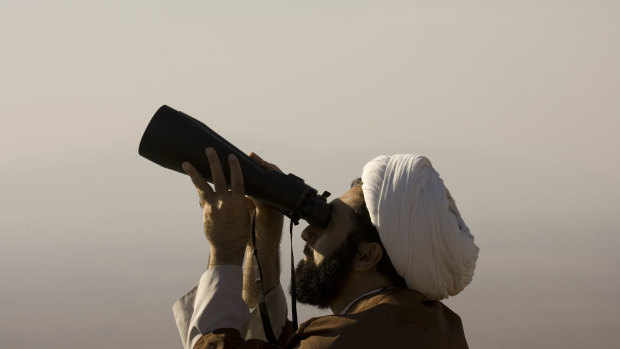 A cleric searches the sky to look for the new moon that signals the start of Eid.