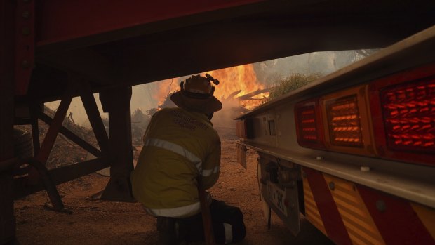 A firefighter battles the out-of-control blaze that has destroyed homes on Perth’s doorstep.  