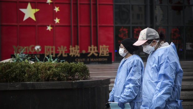 People wear protective masks and clothing  in Wuhan on Monday.