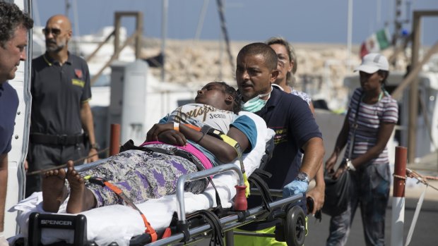 A woman is carried away on a stretcher after disembarking from an Italian Coast Guard ship in the port of Pozzallo, Southern Italy, on Sunday.