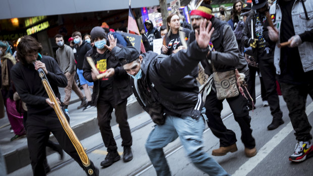 Indigenous protesters do a traditional dance on Bourke Street.