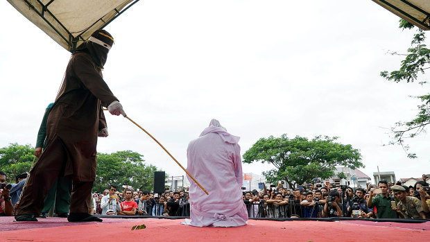 An Acehnese woman being whipped in public for violating sharia law in 2017 for having sex before marriage.