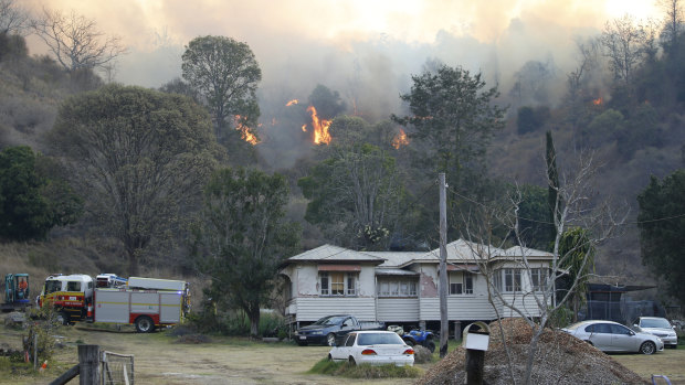 Fire and Emergency crews battle a bushfire near a house in the town of Canungra.