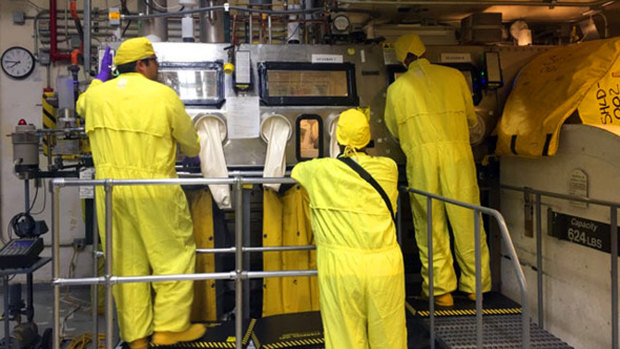 Workers in protective gear handle radioactive waste at Los Alamos National Laboratory.