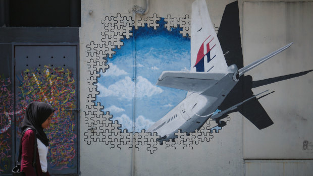 A woman walks past graffiti of the missing Malaysia Airlines Flight MH370 in Kuala Lumpur in 2016.