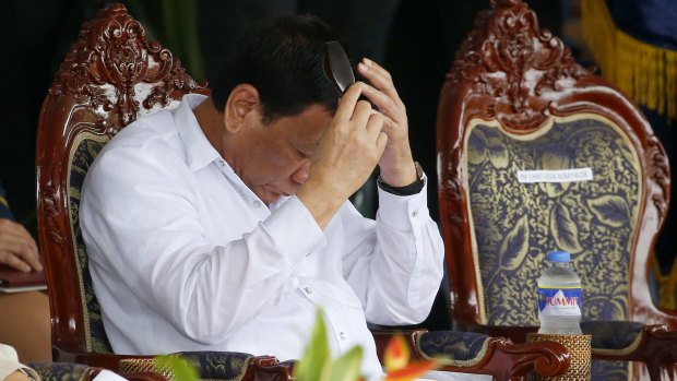 Tired: President Rodrigo Duterte combs his hair after reviewing the police under a sudden downpour at a parade last week.