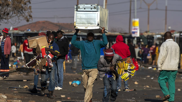 Looters carry items at Letsoho Shopping Centre in Katlehong, east of Johannesburg, South Africa.
