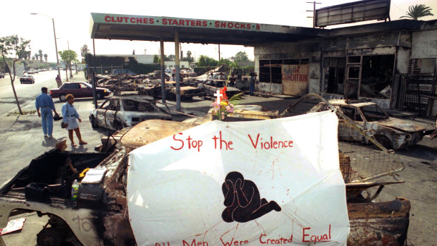 In this May 3, 1992 file photo, a cross, flowers and a banner urging an end to violence adorn the ruins of a service station at Florence and Normandie Avenues in South-Central Los Angeles.