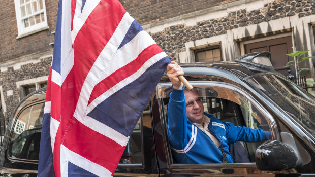 A taxi driver waves a Union Jack flag at Nigel Farage, a day after Britain voted to break out of the EU.