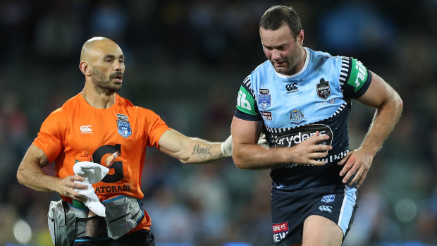 Boyd Cordner is assisted off Adelaide Oval for a head injury assessment by Roosters and Blues trainer Travis Touma.