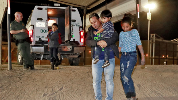 A Honduran man carries his three-year-old son as his daughter and other son follow to a transport vehicle after being detained by US Customs and Border Patrol agents in San Luis, Arizona.