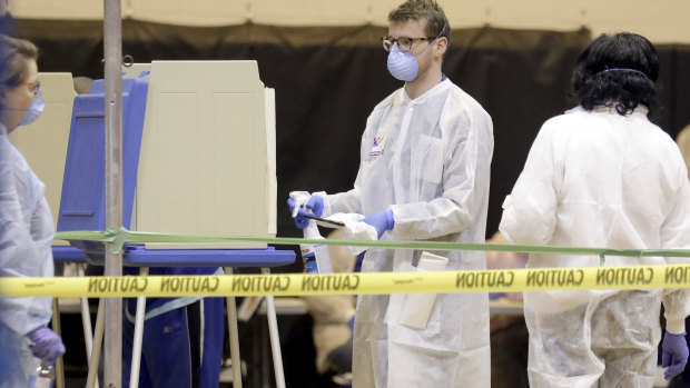 A poll worker sprays down a voting booth after use inside the polling location at Riverside High School  in Milwaukee.