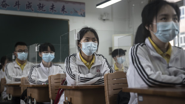 Senior students study in a Wuhan classroom with transparent boards placed on each desk as a precautionary measure. About 57,800 students in their final year went back to school on Wednesday in Wuhan.