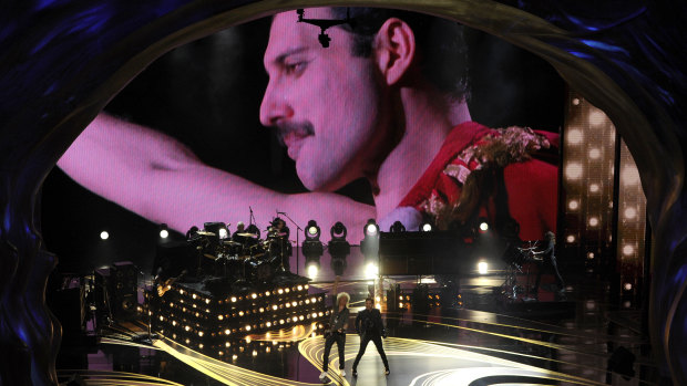 An image of Freddie Mercury appears on screen as Brian May, left, and Adam Lambert of Queen perform at the Oscars.