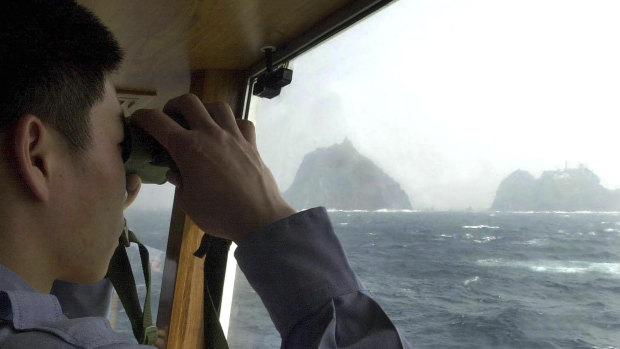 A South Korean coast guard looks at Dokdo islets, known as Takeshima in Japanese, from the patrol ship Sambong-ho on the East Sea, South Korea.