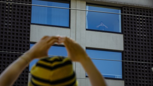 A Bangladeshi refugee signals 'joy' to protestors outside a Carlton hotel.