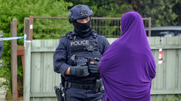 A police officer speaks to a woman who arrived at the Werribee home of Shire Ali's parents on Saturday.